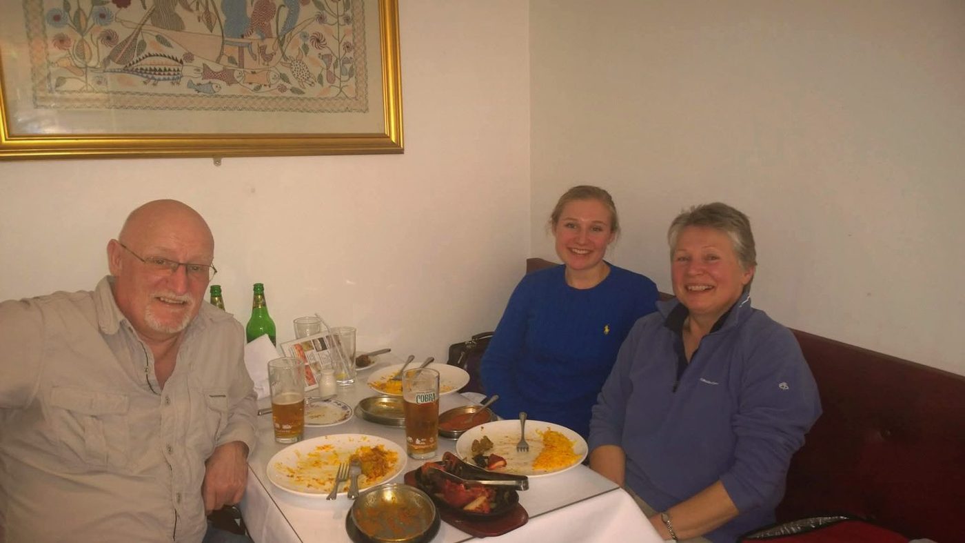 Three customers smiling over curry, rice and Cobra beer at a Balti House table
