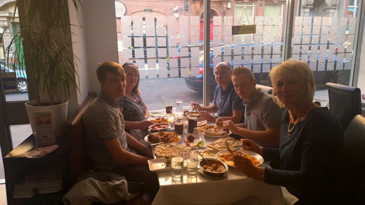 Six diners sharing curry, naan and karahi dishes at a Balti House window table