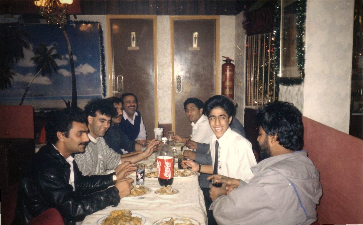Balti House staff sharing plates of curry and rice at a long table decorated for Christmas